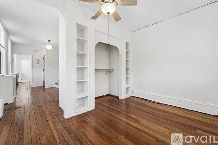 A spacious room with wooden floors and white walls.