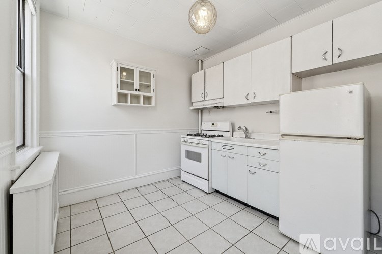 A white kitchen with a refrigerator, oven, and sink.