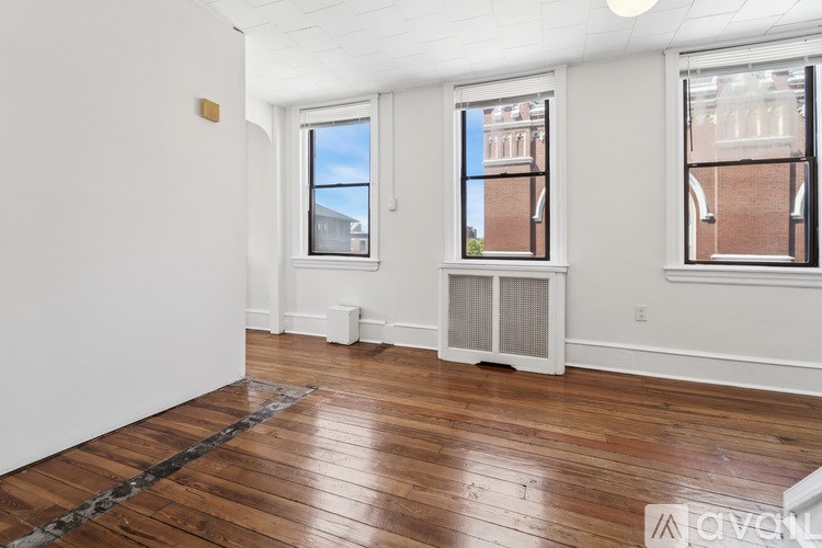 A room with wooden floors and two windows.