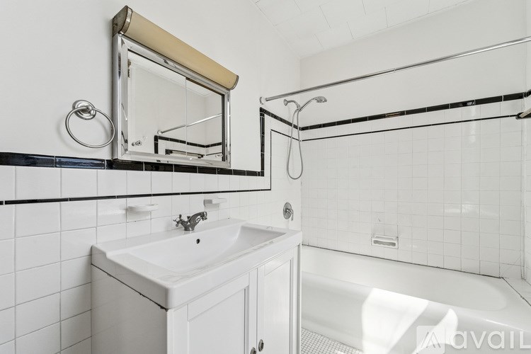 A white bathroom with a sink, mirror, and bathtub.