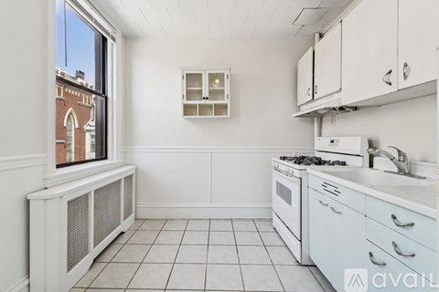 A kitchen with white cabinets and a window overlooking a brick building.