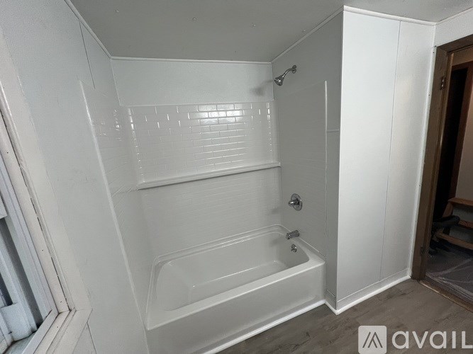 A white bathroom with a bathtub and a shower head.
