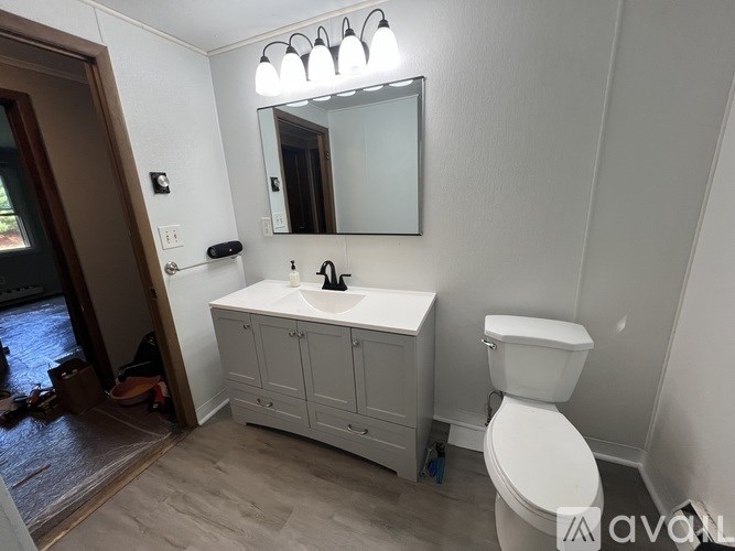 A bathroom with a white toilet, sink, and mirror.