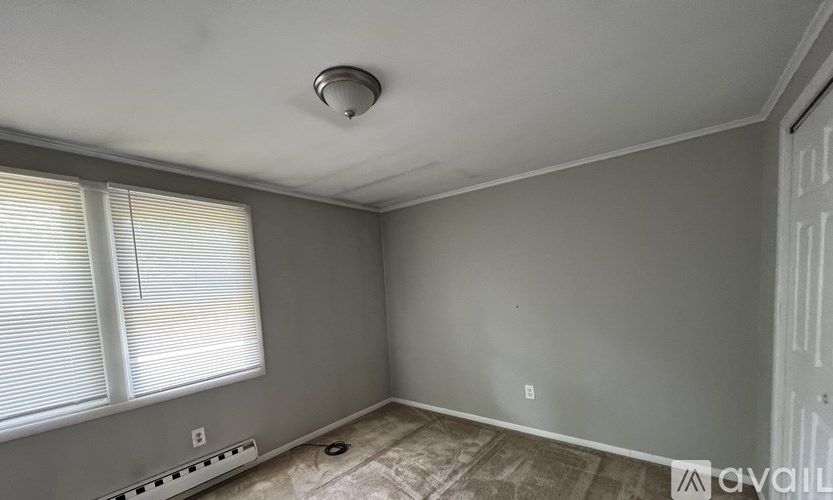 A room with a window, a ceiling fan, and a door.