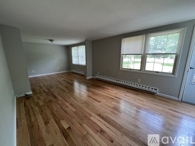 A room with wooden flooring and a window with blinds.