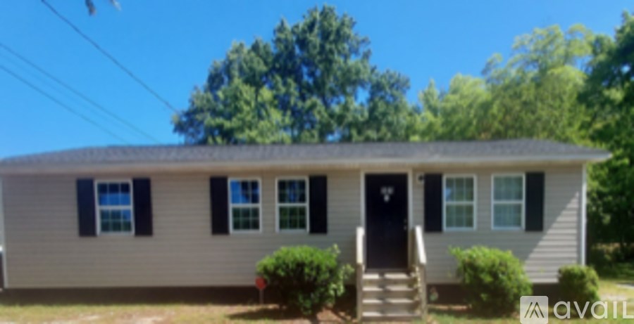 A house with a black door and a sign that says "available" in front of it.