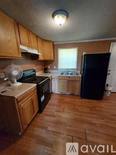 A kitchen with wooden cabinets and a black fridge.