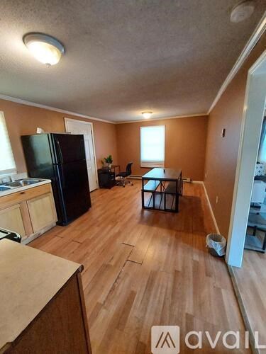 A kitchen with a black fridge and wooden floors.