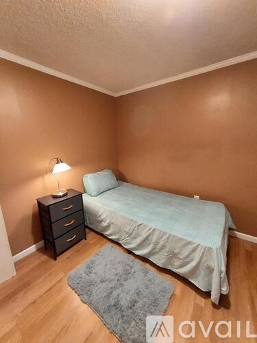 A bedroom with a bed, nightstand, and lamp.