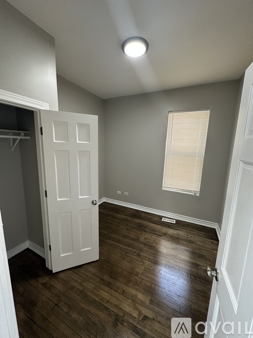 A room with a white door and wooden flooring.