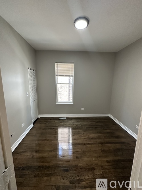 A room with wooden flooring and a window with blinds.