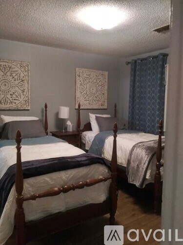 A bedroom with two beds and two lamps.