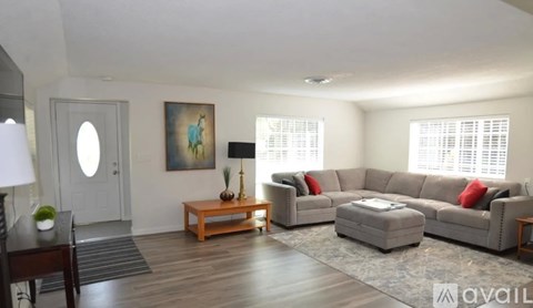 A living room with a grey couch, a wooden table, and a painting on the wall.