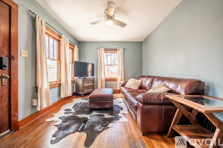 A living room with a brown leather couch and a cowhide rug.