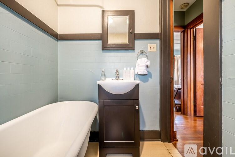 A bathroom with a white bathtub and a brown vanity.