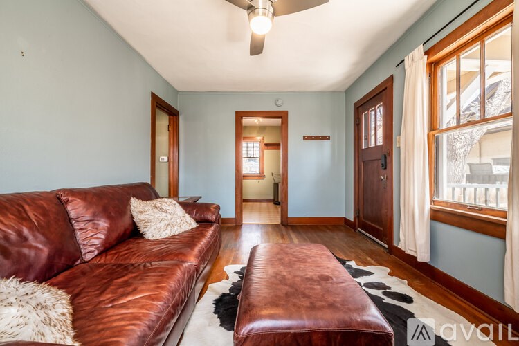 A living room with a brown leather couch and a cowhide rug.