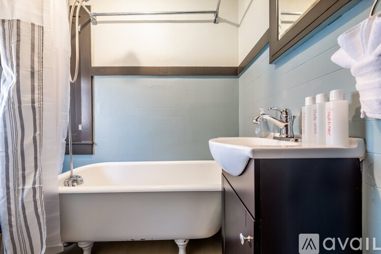 A bathroom with a white bathtub and a black cabinet with a mirror above it.