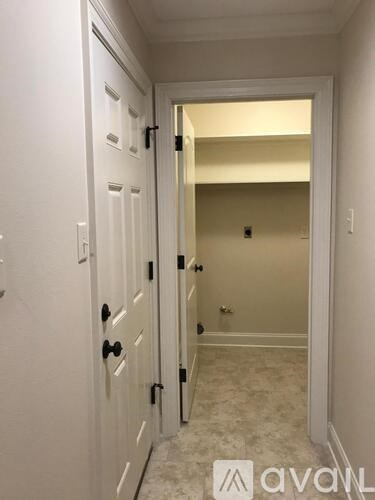 A hallway with a white door and a white wall.