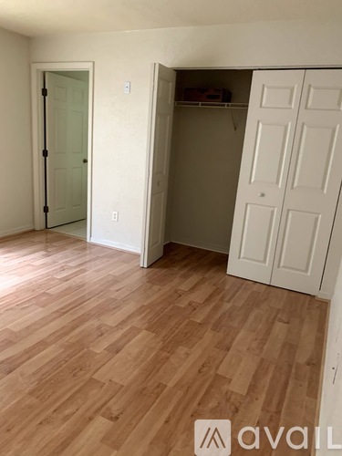 A room with a white door and a white closet with wood flooring.
