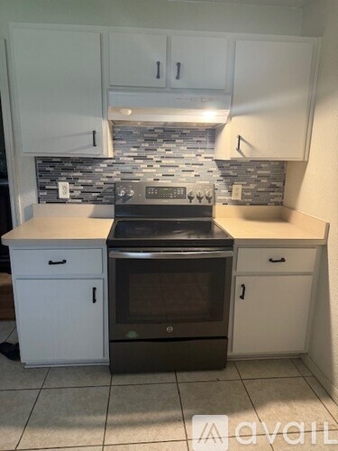 A kitchen with a black oven and white cabinets.
