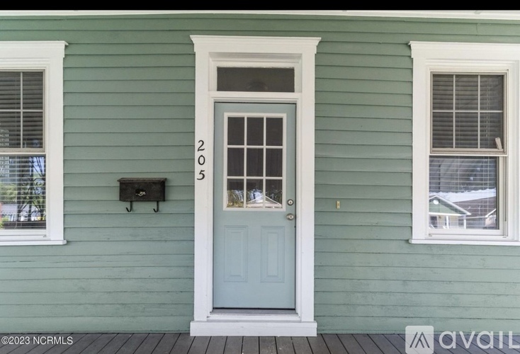 A green house with a blue door and mailbox number 2053.