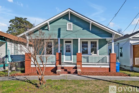A house with a blue front and a tree in front of it.