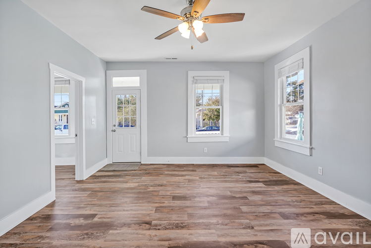 A spacious room with a ceiling fan and wooden flooring.