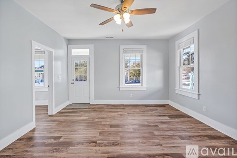 A spacious room with a ceiling fan and wooden flooring.