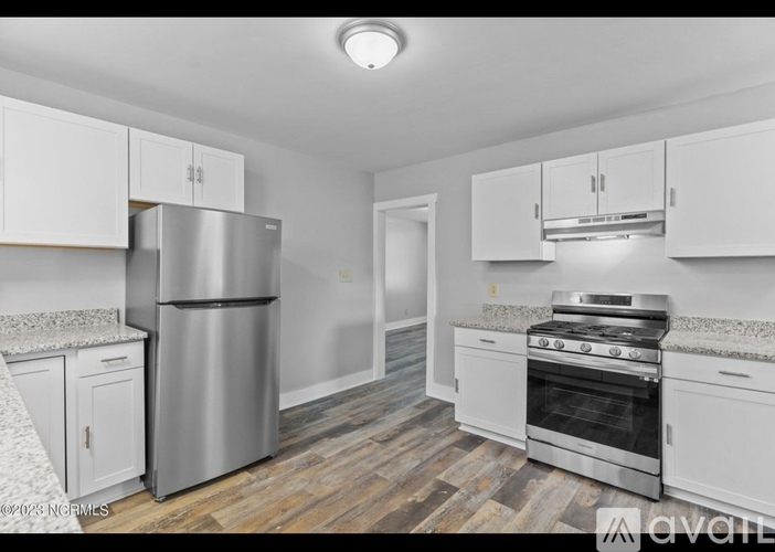 A kitchen with white cabinets and a stainless steel refrigerator.