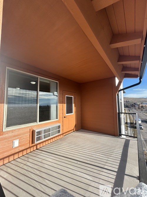 A balcony with a wooden floor and a brown wall.