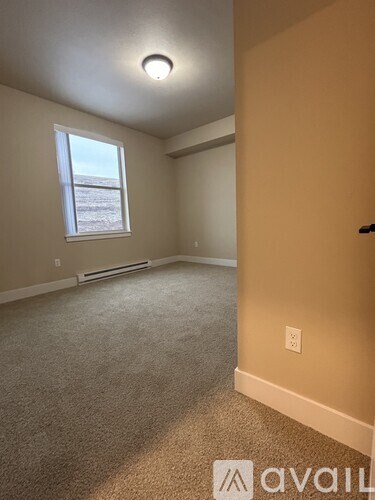 A room with a window and a carpeted floor.