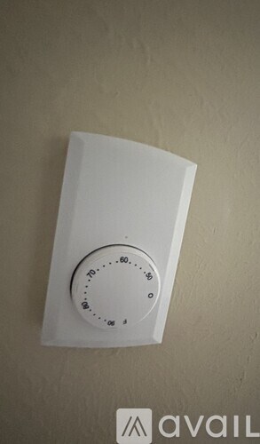 A white thermostat on a beige wall.