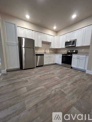 A kitchen with wooden flooring and white cabinets.