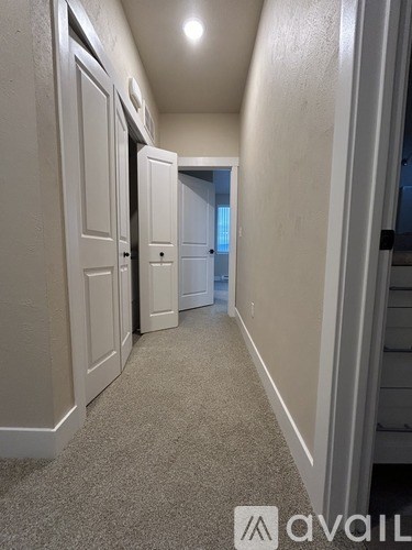 A hallway with a carpeted floor and white walls.