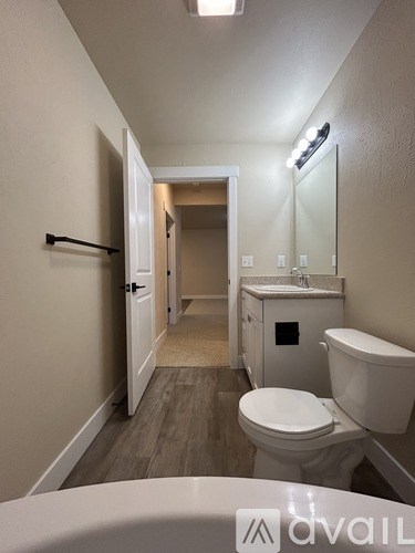 A bathroom with a toilet, sink, and mirror.