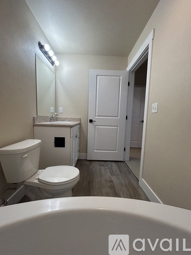 A bathroom with a toilet, sink, and mirror.