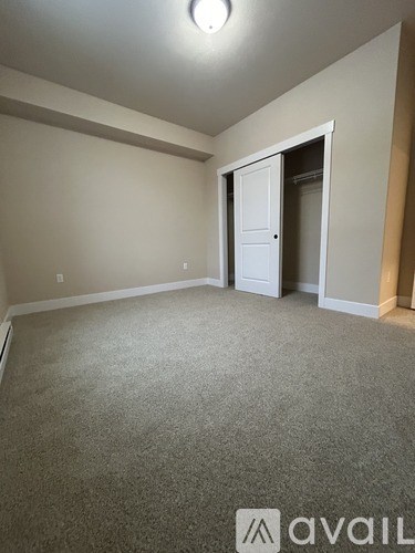 A room with a carpeted floor and a doorway leading to another room.