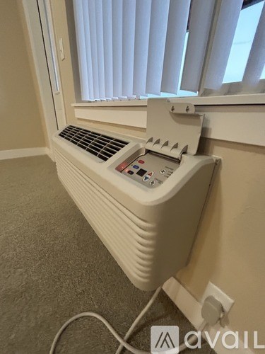 A white electric heater plugged into a wall socket.