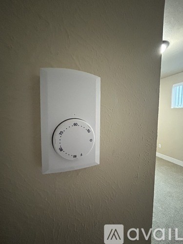 A white thermostat is mounted on a wall.