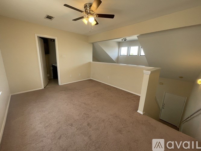 A spacious room with a ceiling fan and carpeted floor.