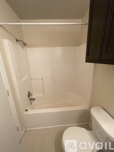 A bathroom with a toilet, tub, and cabinet.