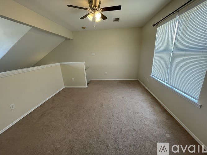 A room with a ceiling fan and carpeted floor.