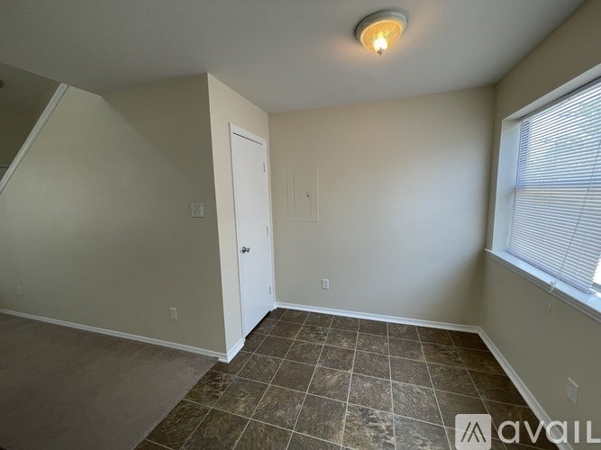 A room with tiled flooring and a window with blinds.