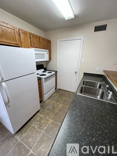 A kitchen with a white fridge, microwave, and stove top oven.