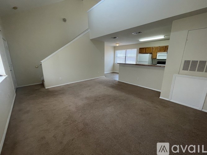 A spacious room with beige carpeting and white walls.