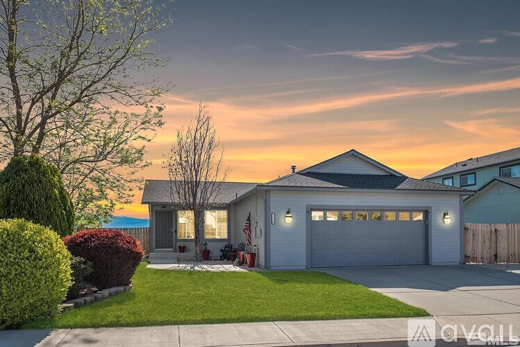 A house with a garage and a tree in front of it.