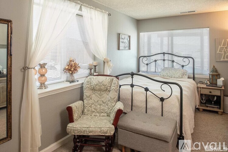 A bedroom with a bed, chair, and window.