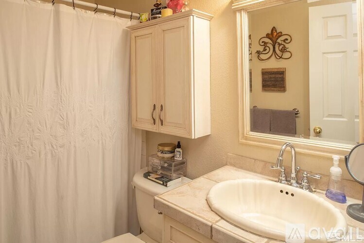 A bathroom with a white sink and a white shower curtain.