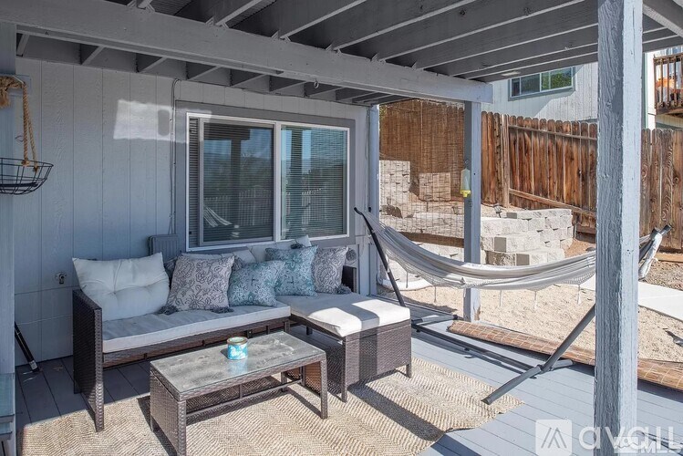 A patio with a hammock and a table.