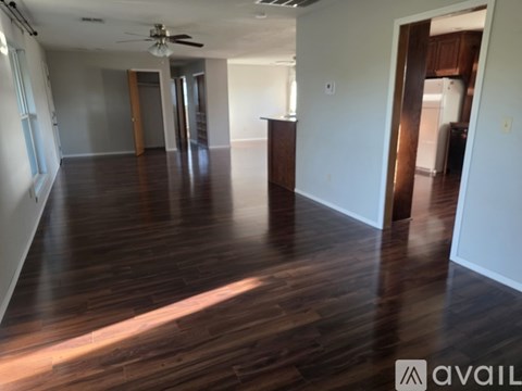 A spacious room with wooden floors and a ceiling fan.